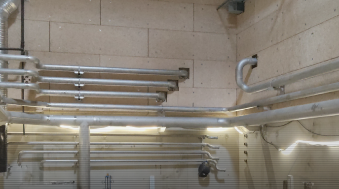 Tuyaux métalliques fixés au mur dans un espace intérieur.